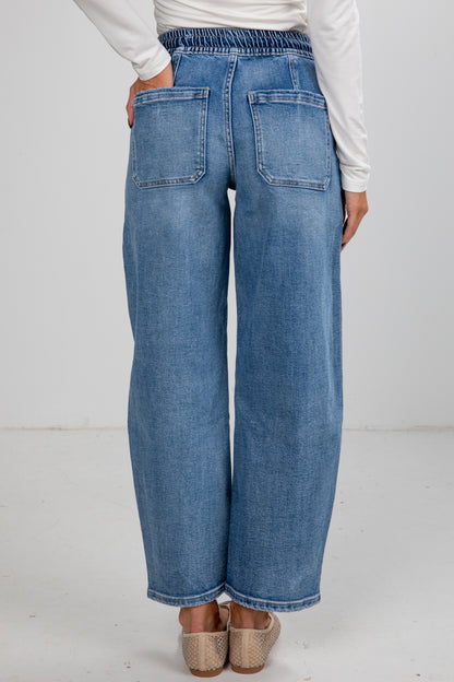 Person wearing blue jeans on a plain background