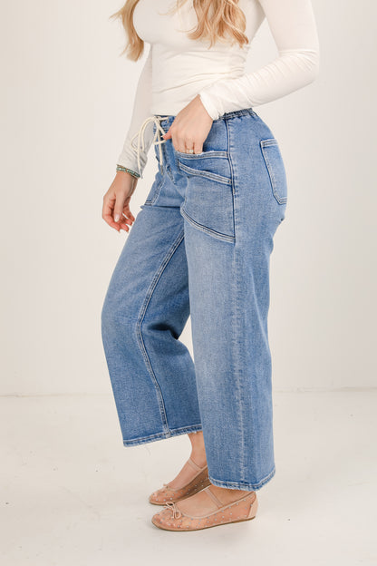Person wearing blue jeans and a white top on a plain background