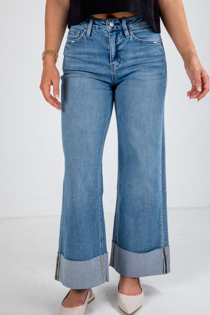 Person wearing blue flared jeans on a white background