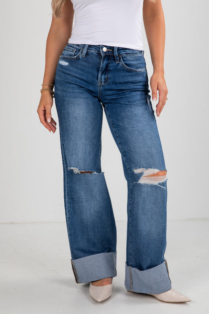 Person wearing blue distressed jeans on a white background