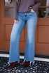 Person wearing blue flared jeans and brown shoes standing in front of a brown door.