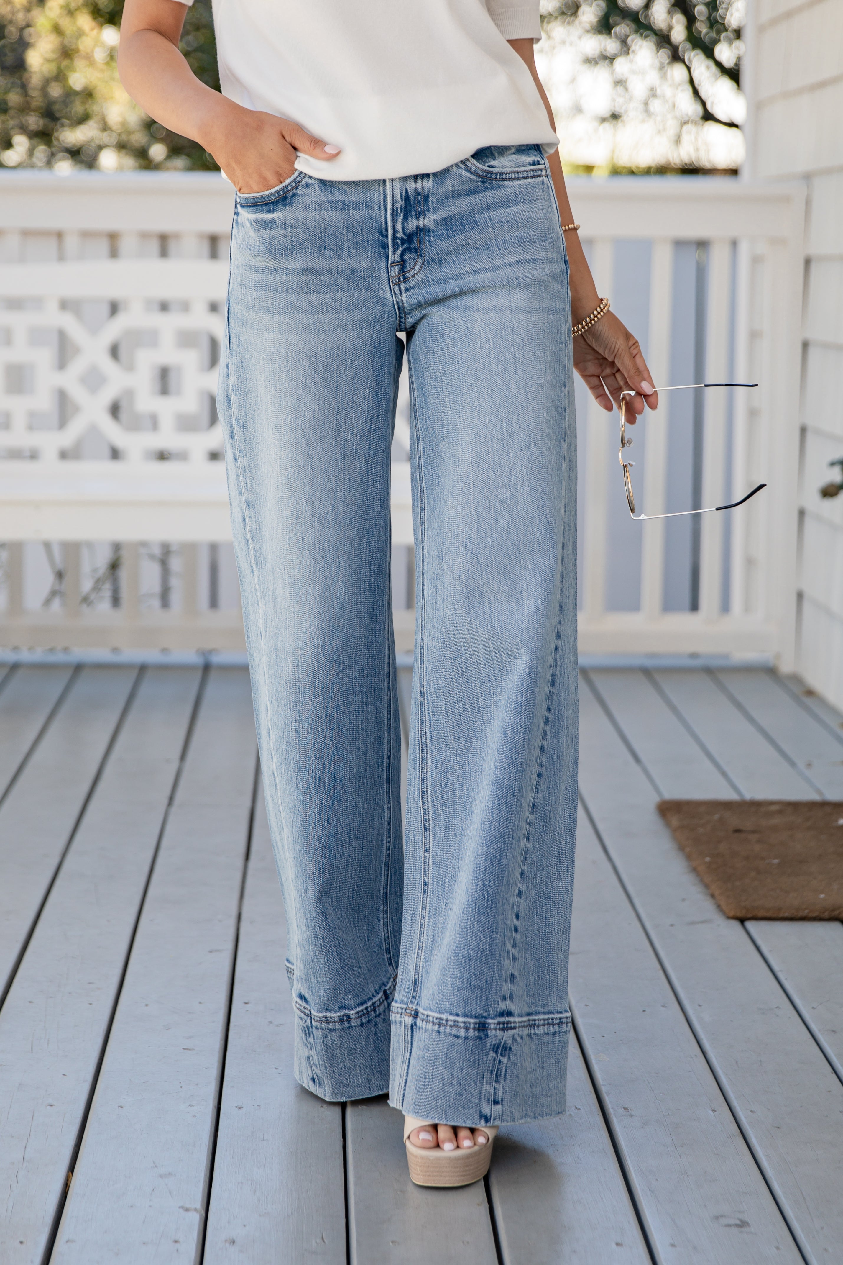 Person wearing light blue jeans on a wooden deck