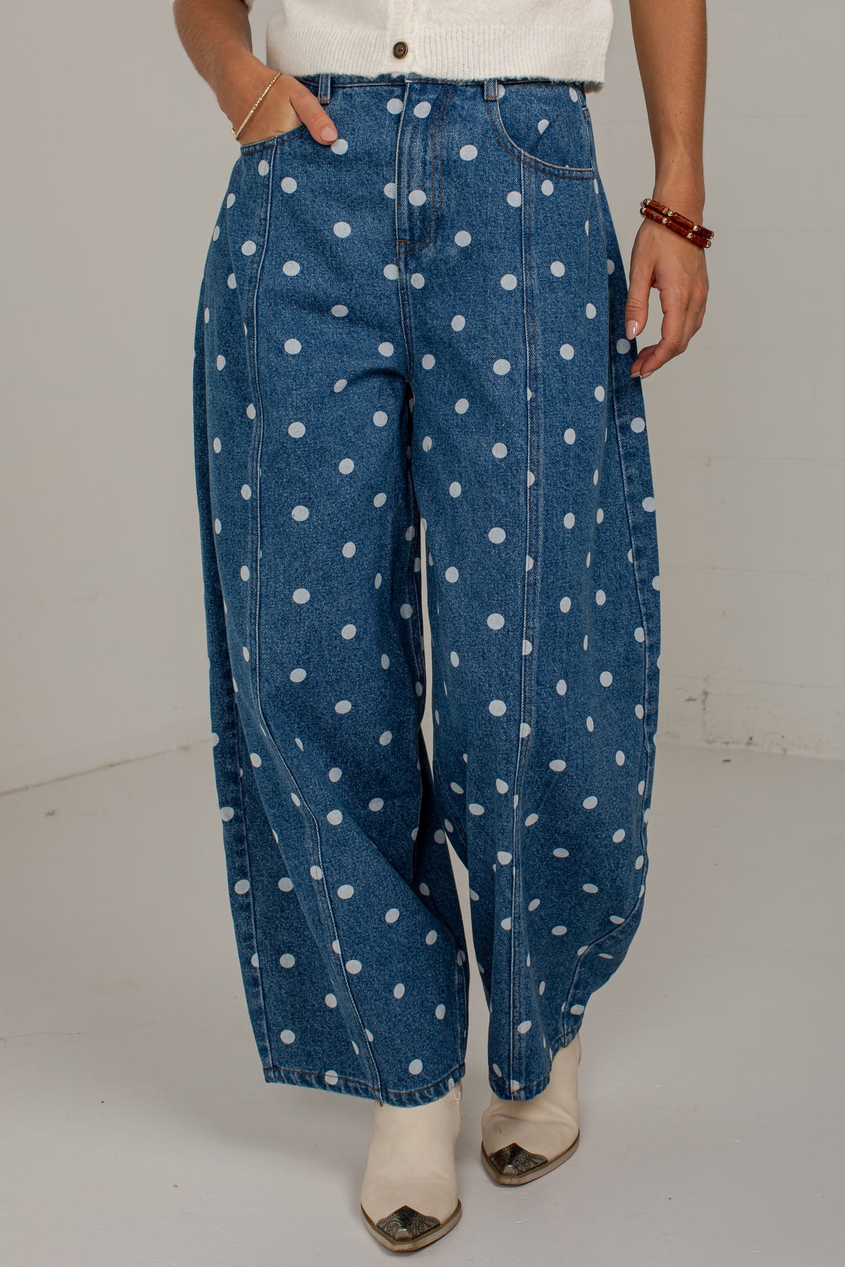 Model posing in medium wash polka dot barrel jeans with one hand tucked into the front pocket.
