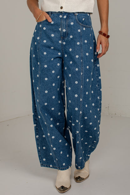 Model posing in medium wash polka dot barrel jeans with one hand tucked into the front pocket.