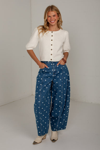 Front detail of medium wash polka dot jeans showing the high-rise fit, pockets, and barrel-leg silhouette.