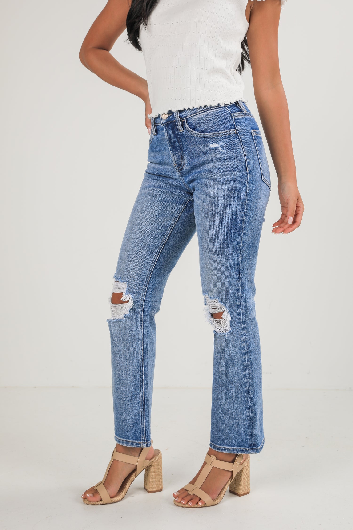 Person wearing distressed blue jeans on a white background