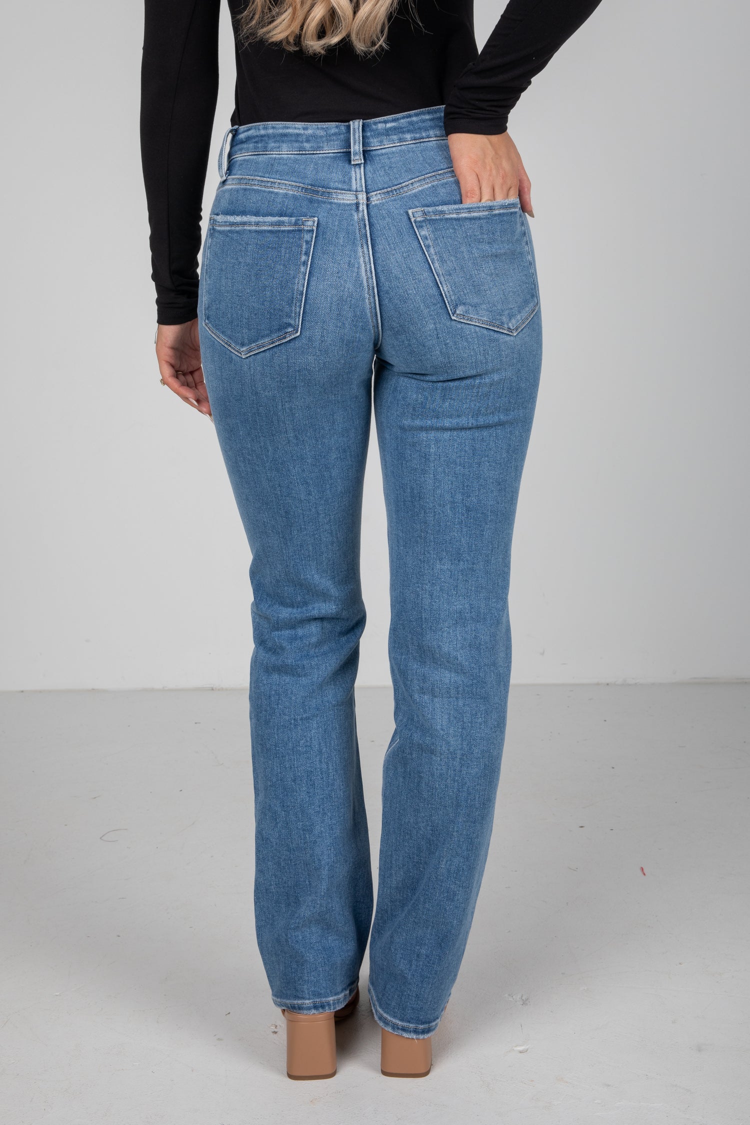 Person wearing blue jeans on a plain background