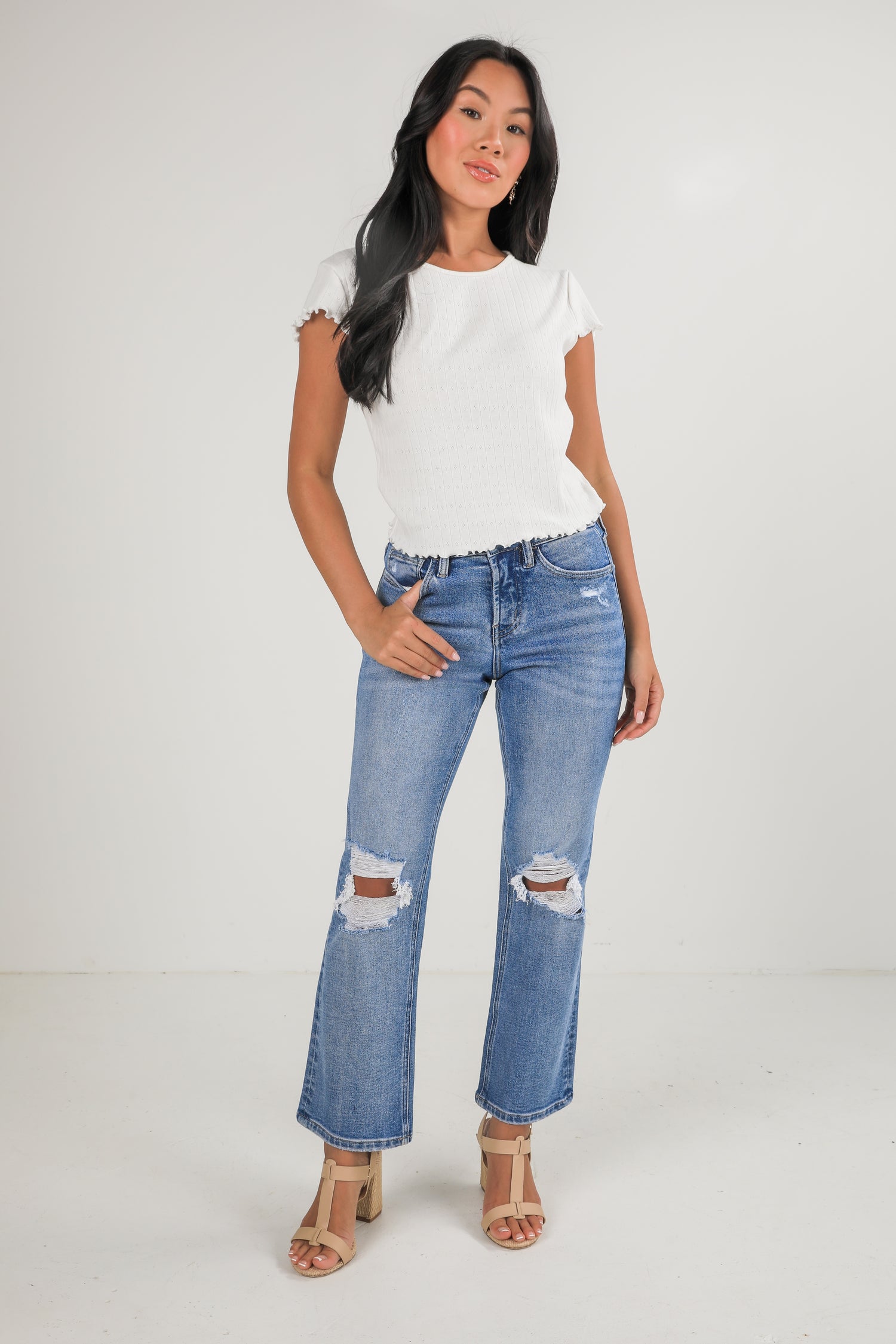Woman wearing a white t-shirt and blue jeans with a white background