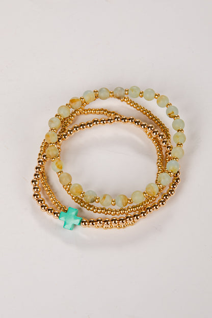 Set of gold and green beaded bracelets on a light background