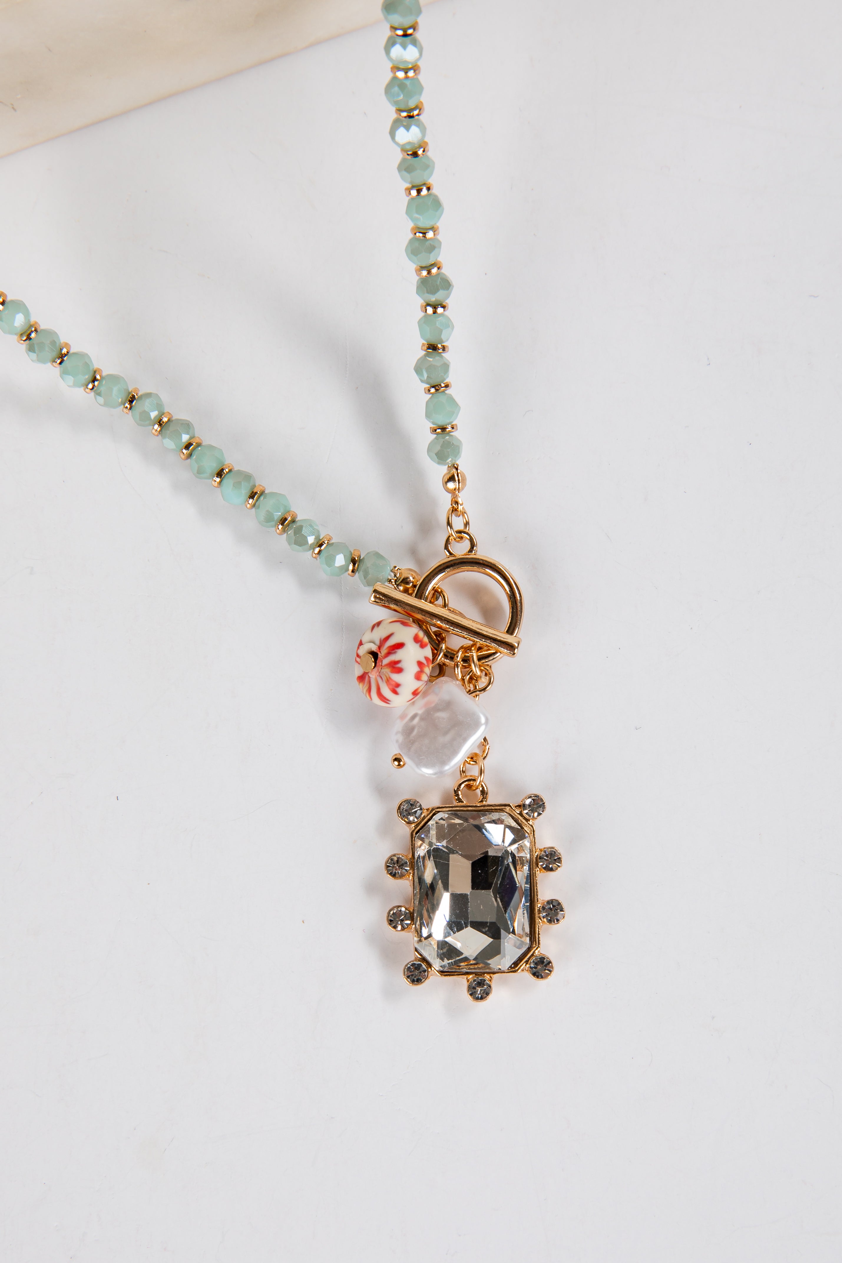 Necklace with a pendant featuring a green gemstone on a white background