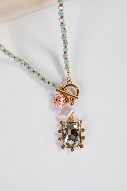 Necklace with a pendant featuring a green gemstone on a white background