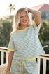 Woman wearing a yellow and blue striped outfit on a blurred outdoor background