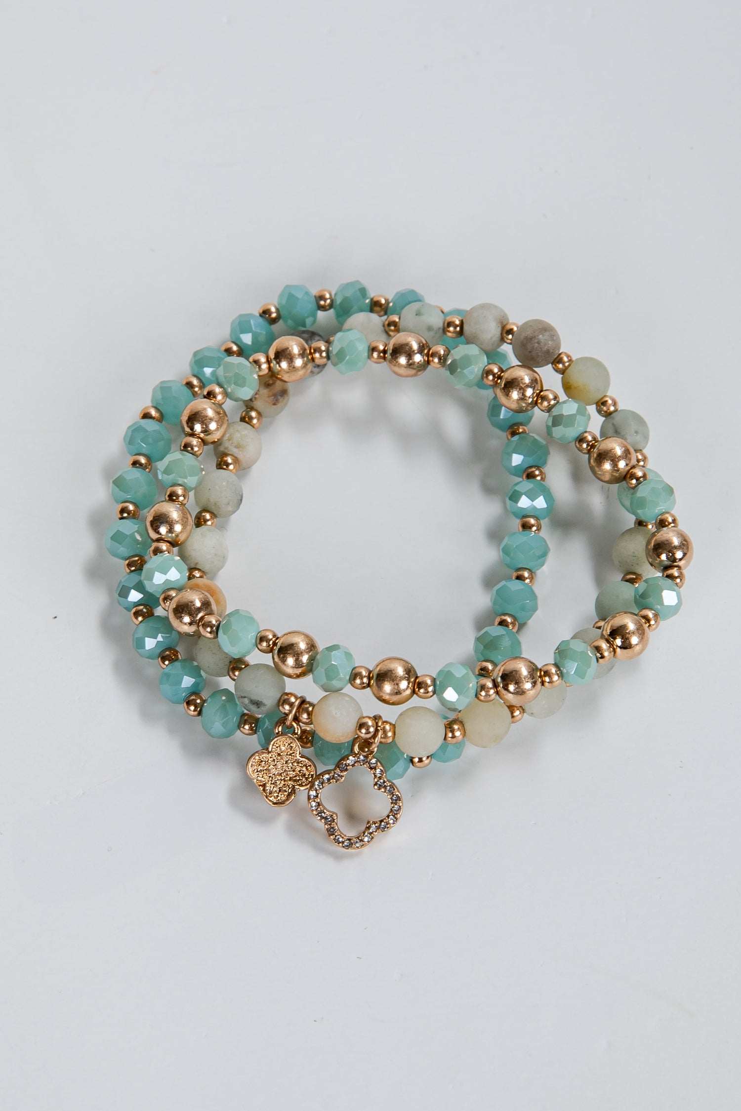 Set of turquoise and gold beaded bracelets on a light gray background