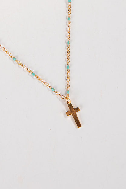Gold necklace with a cross pendant on a light gray background