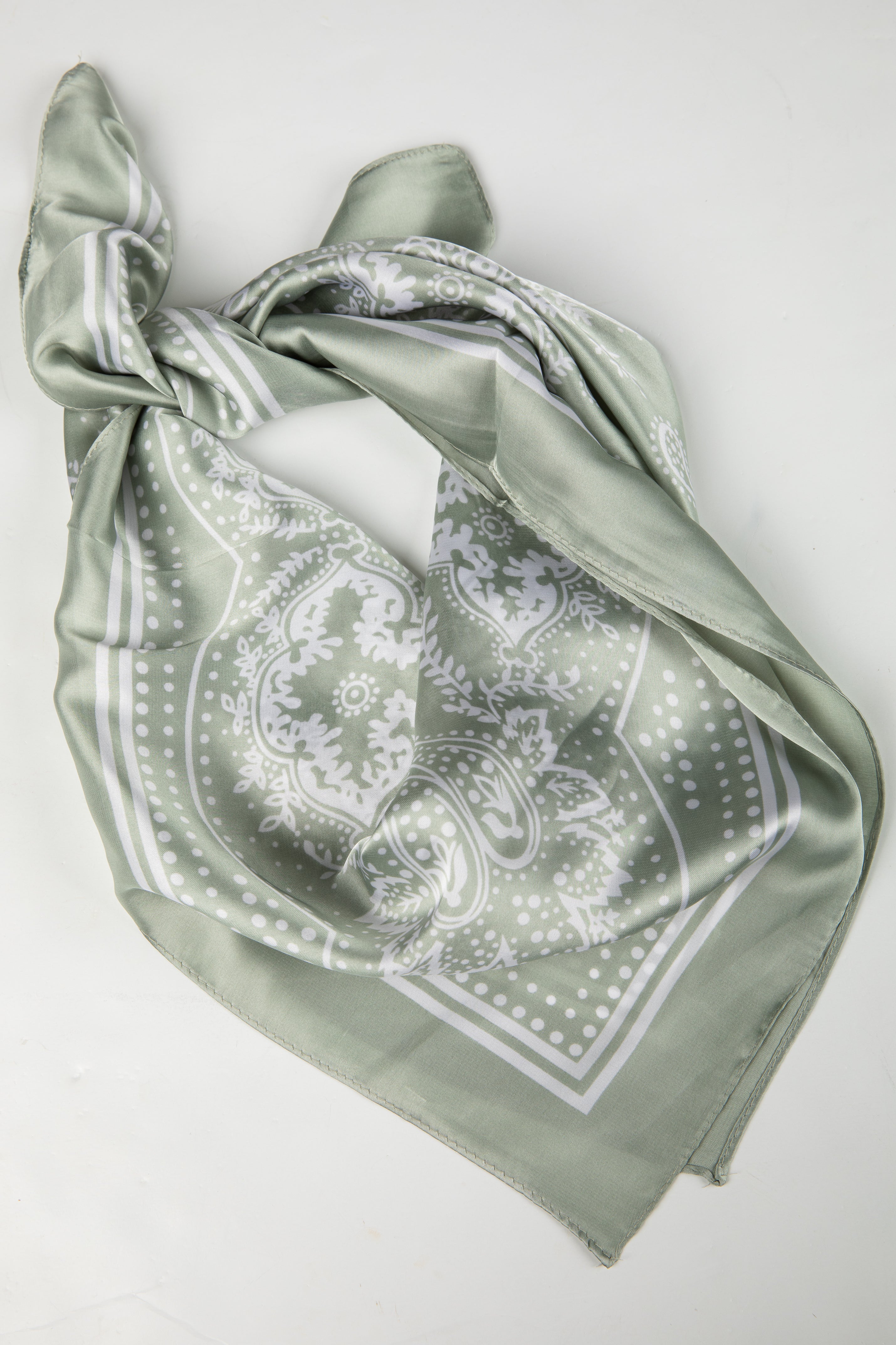Green scarf with white pattern on a light gray background
