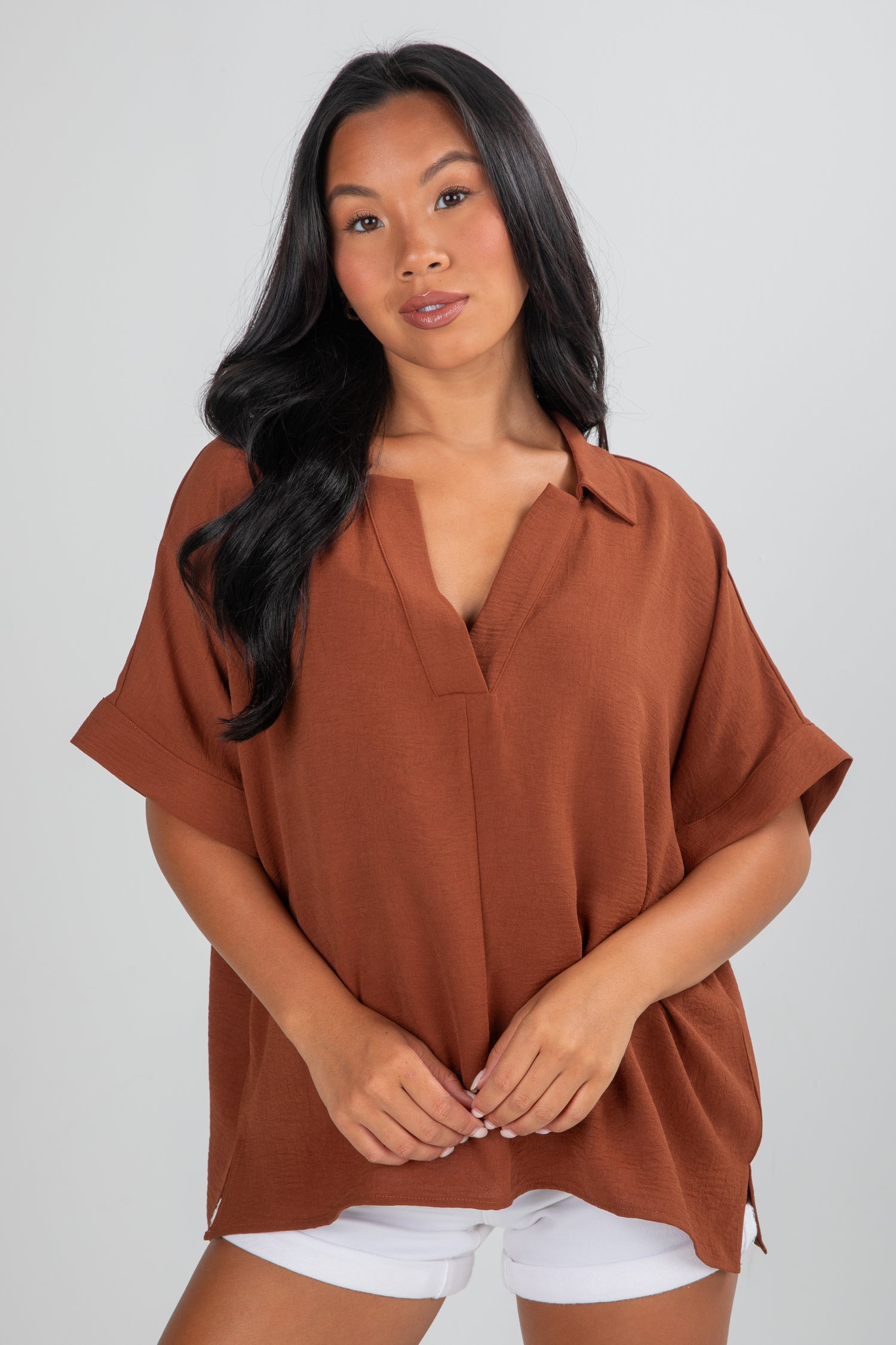 Woman wearing a brown blouse against a plain background