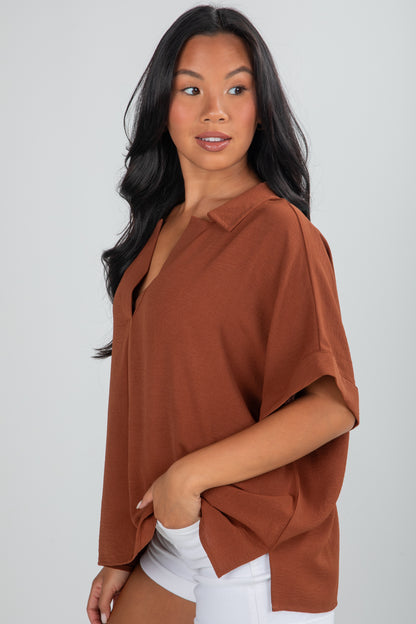Woman wearing a brown blouse against a plain background