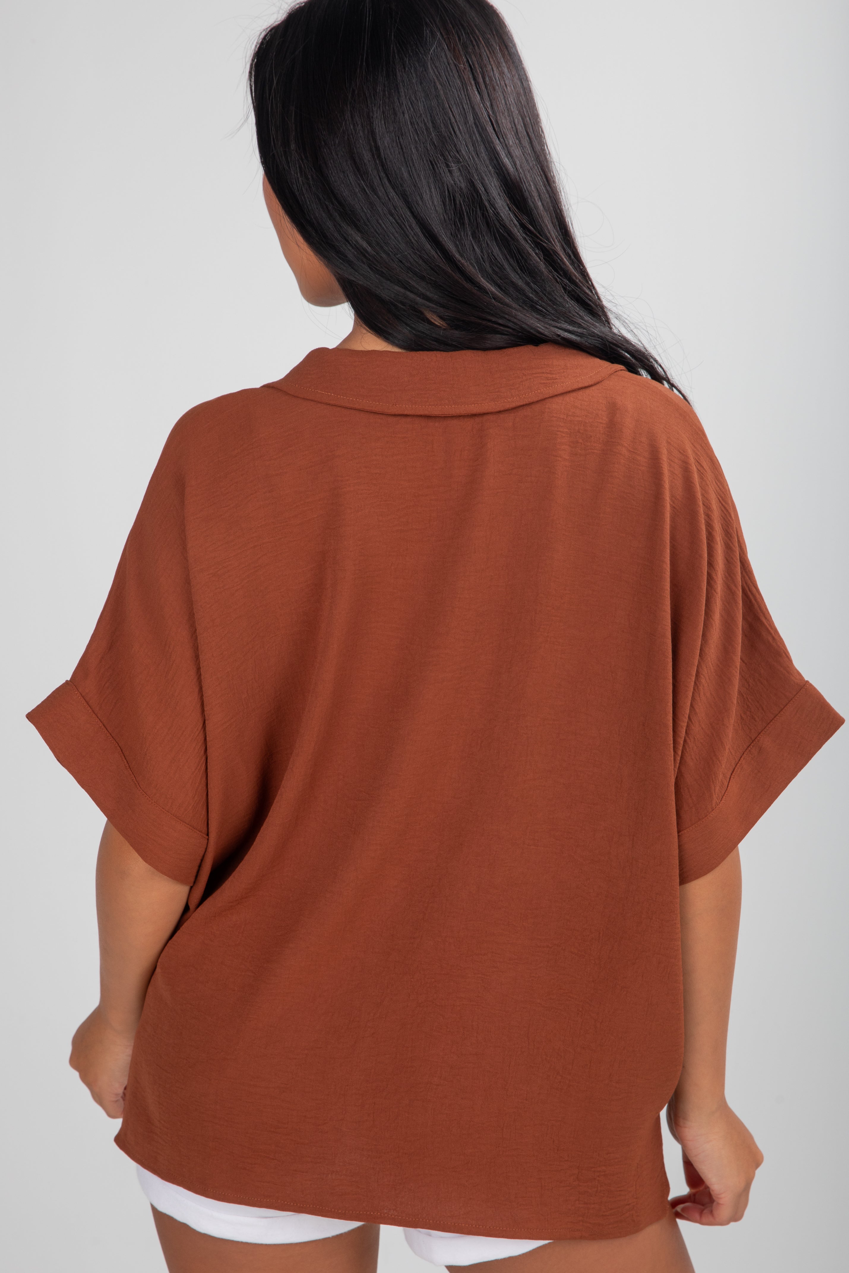 Person wearing a brown oversized shirt on a white background