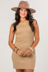 A woman modeling a sleeveless, knee-length beige dress with a wide-brimmed taupe hat, accessorized with bracelets, against a plain light gray background.