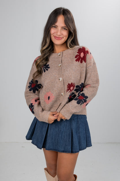Woman wearing a floral cardigan and denim skirt on a white background