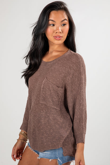Woman wearing a brown sweater with a pocket on a white background
