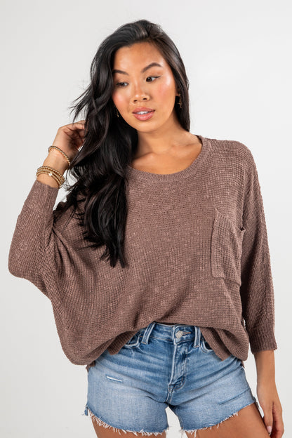 Woman wearing a brown sweater and denim shorts on a white background