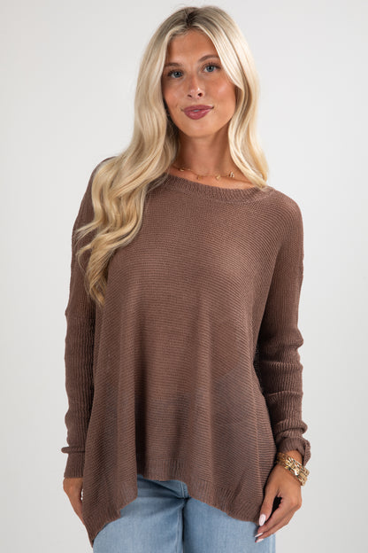 Woman wearing a brown sweater and blue jeans on a white background