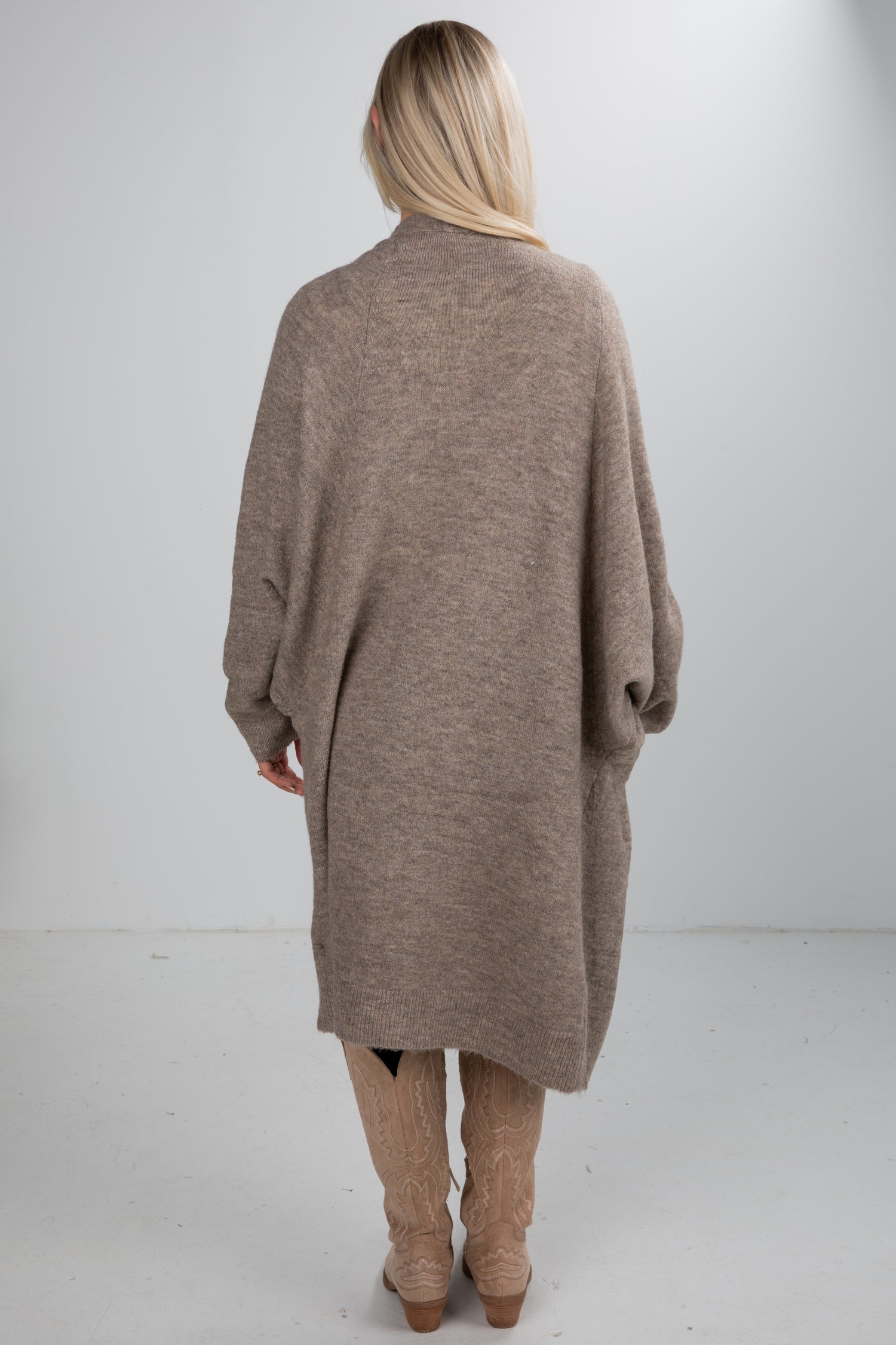 Person wearing a long brown cardigan on a white background