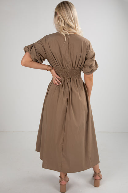 Woman wearing a brown dress with puff sleeves on a white background