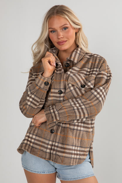 Woman wearing a plaid jacket with a neutral background