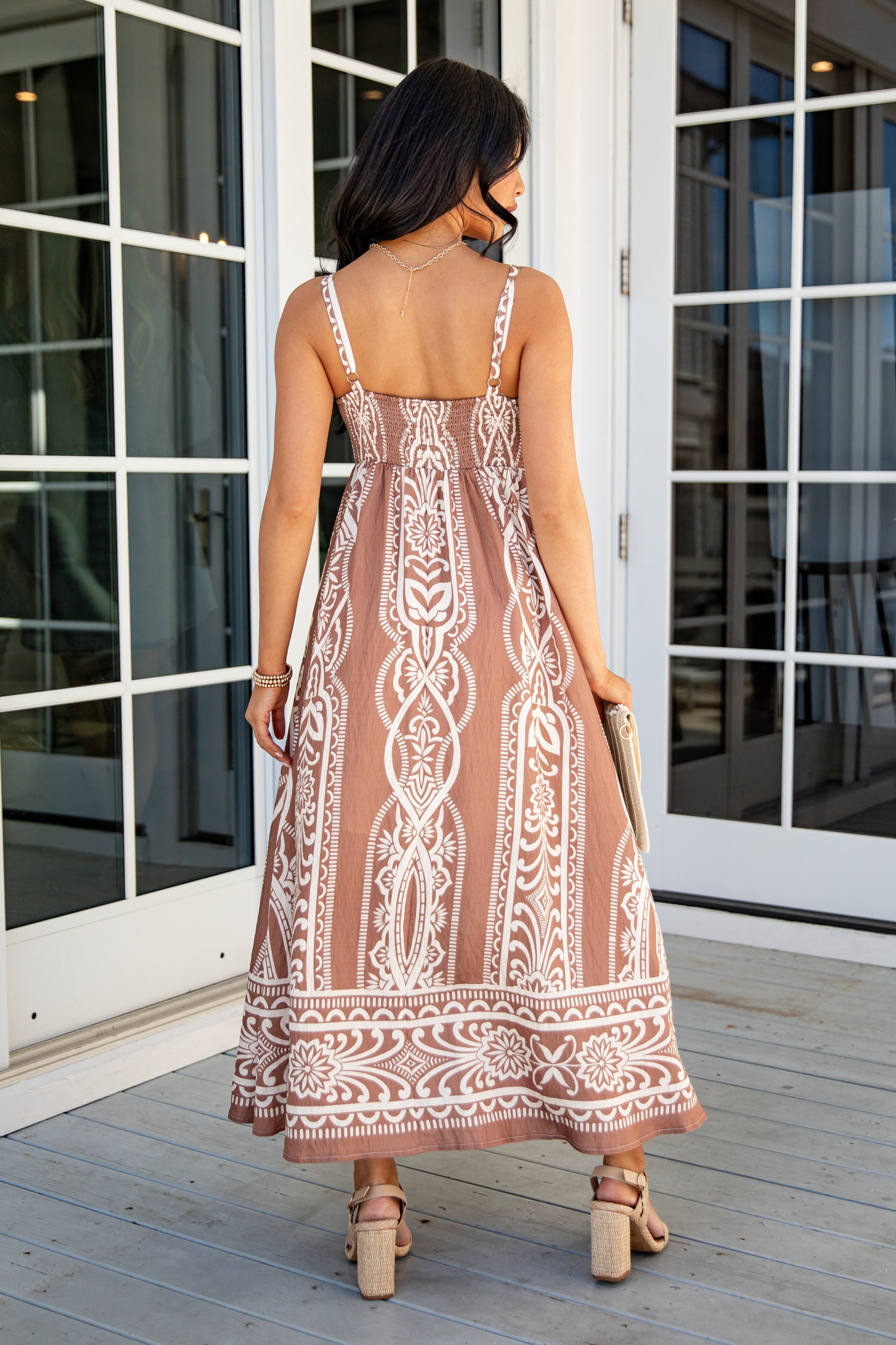 Woman wearing a patterned dress standing on a wooden deck.