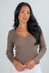 Woman wearing a brown ribbed sweater against a plain background