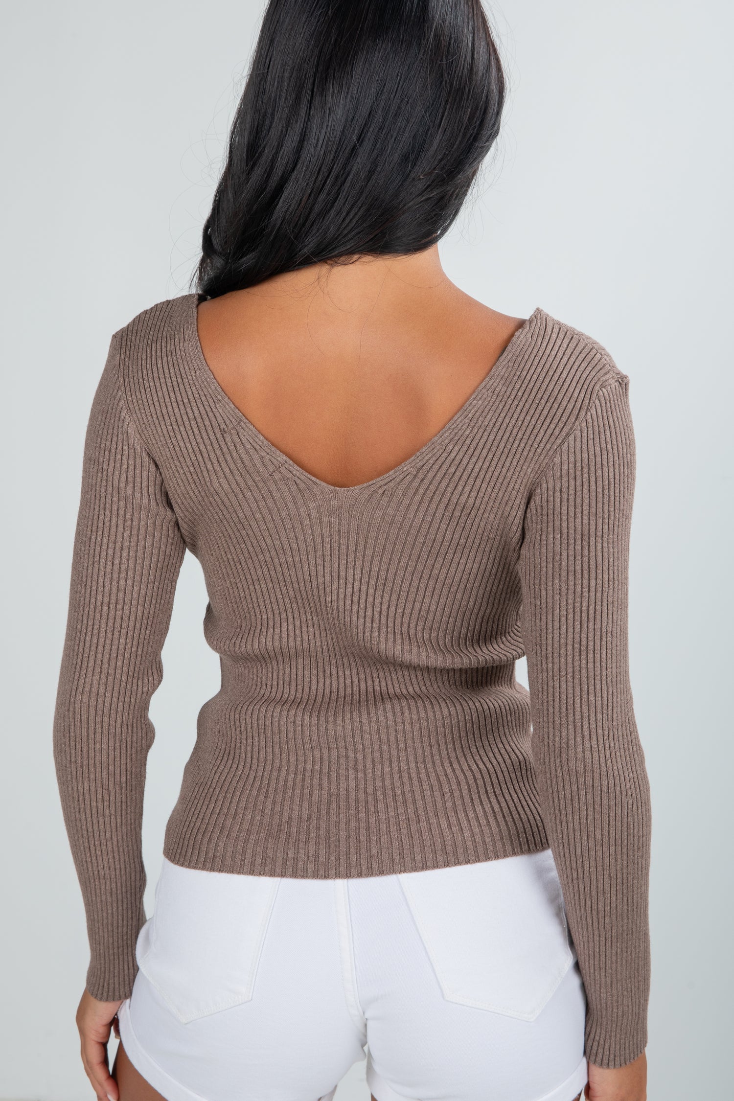 Brown ribbed sweater worn by a person on a plain background