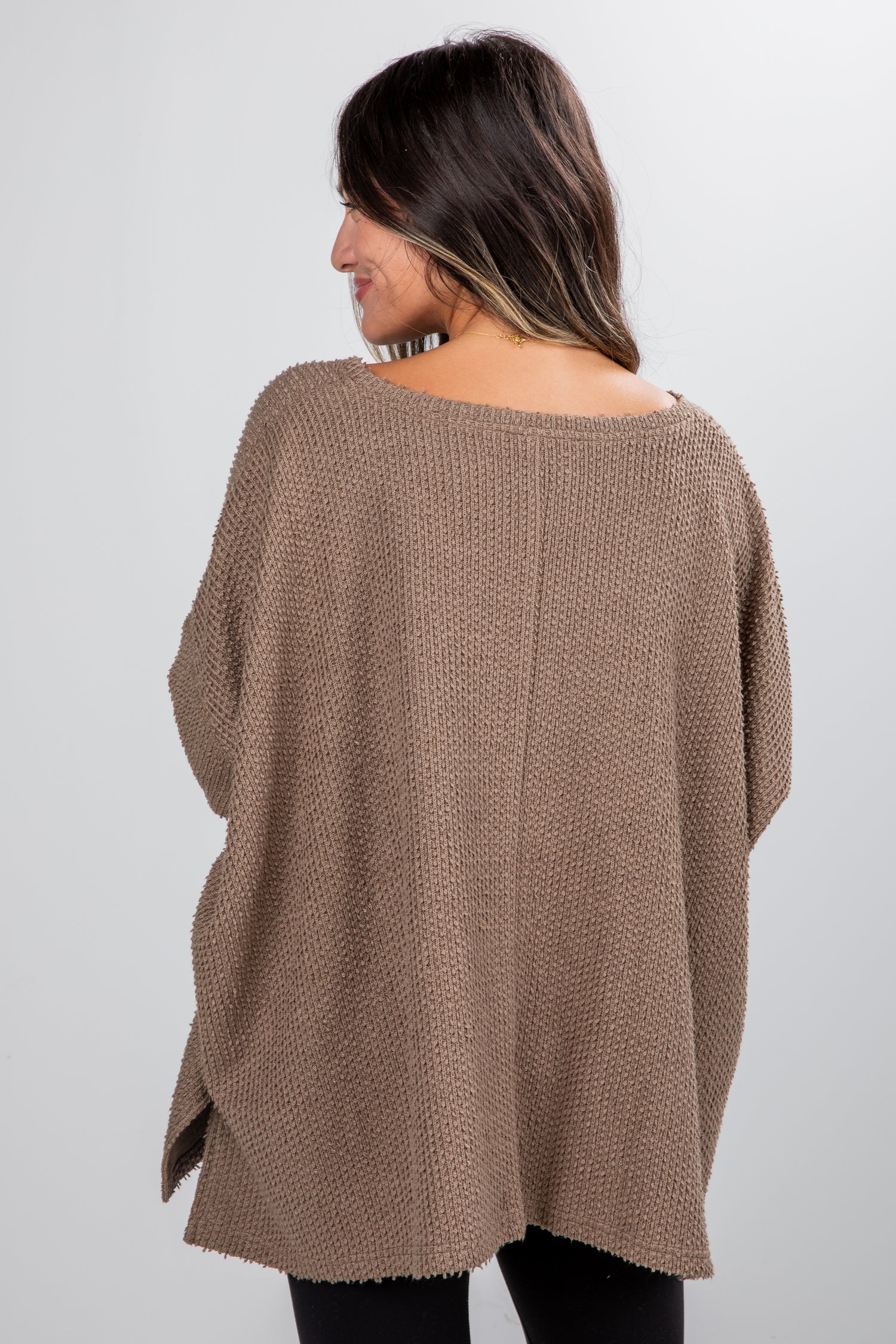 Woman wearing a brown poncho against a white background