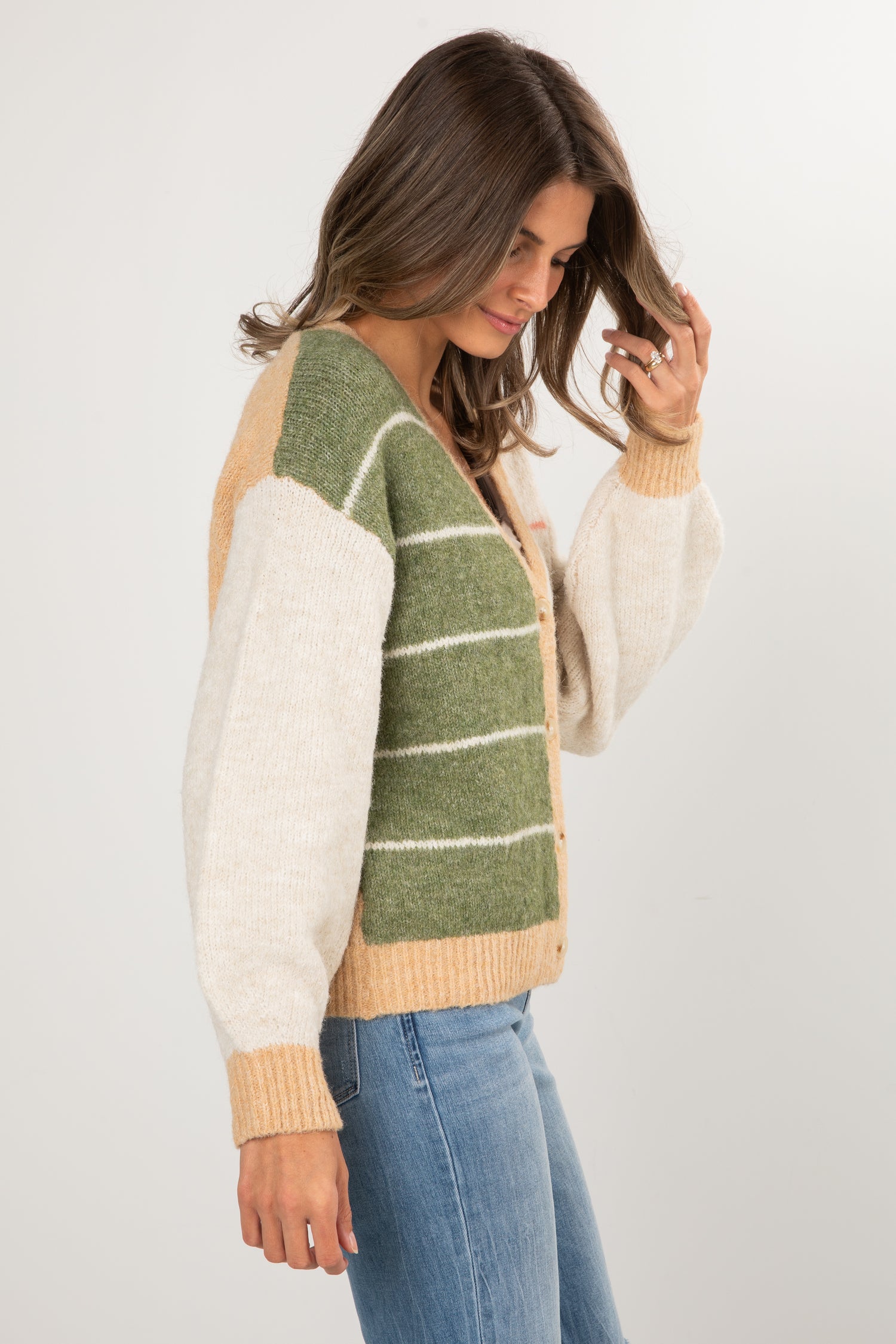 Woman wearing a green and beige striped sweater with a white background