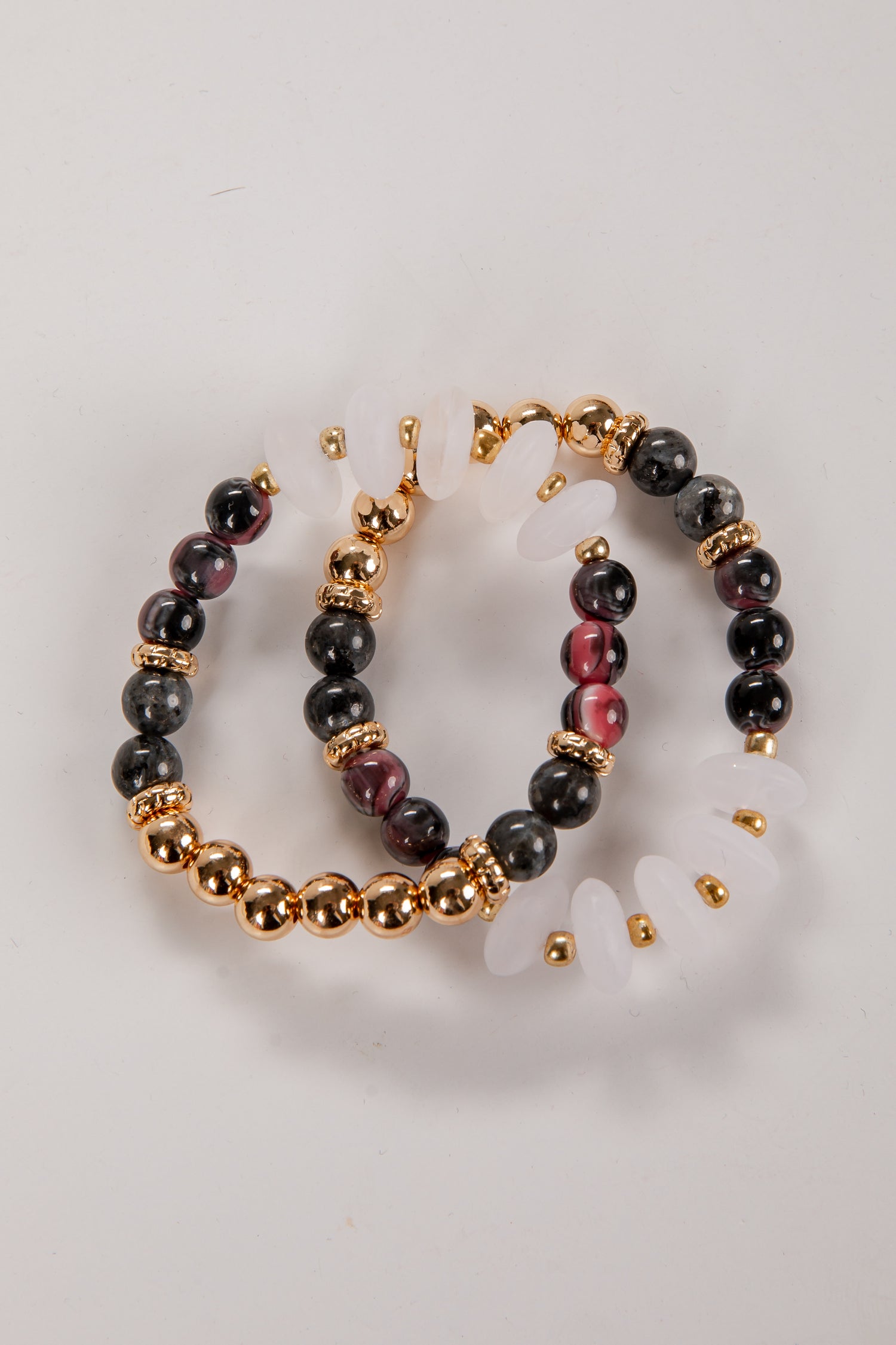 Pair of hoop earrings with black and gold beads on a light gray background