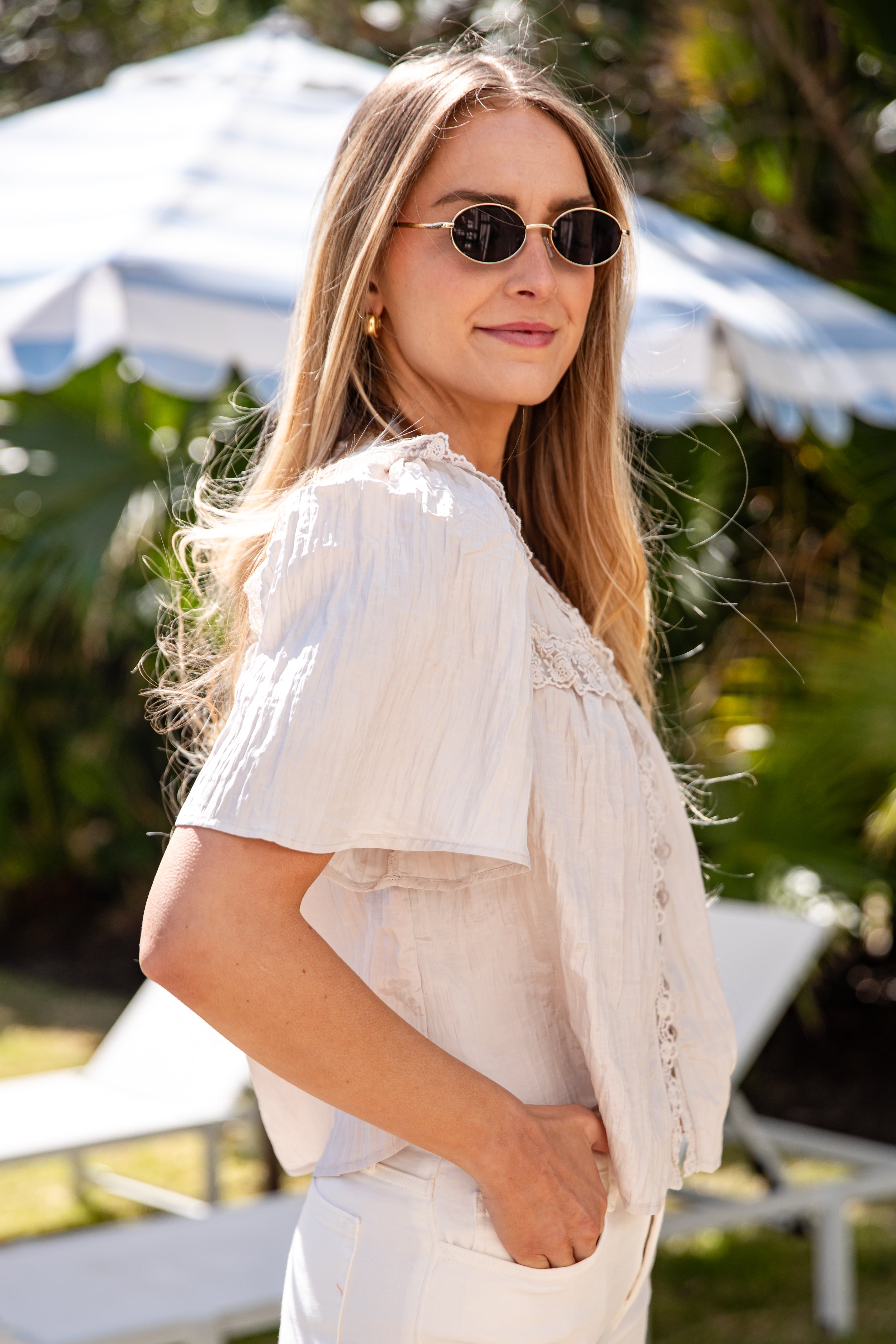 Woman wearing sunglasses and a light-colored outfit in an outdoor setting