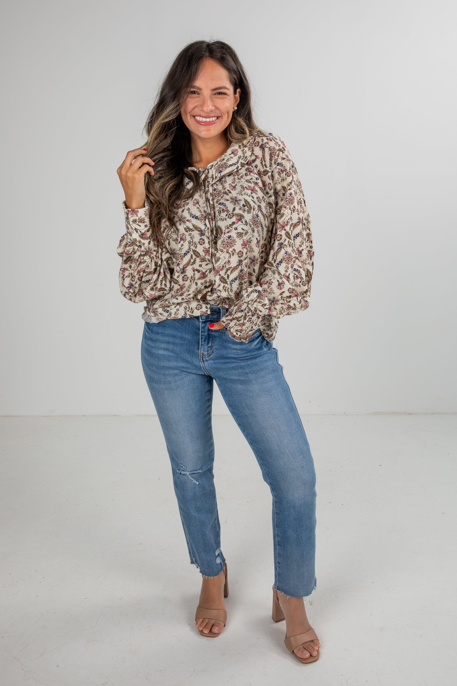 Woman wearing a floral hoodie and blue jeans on a white background