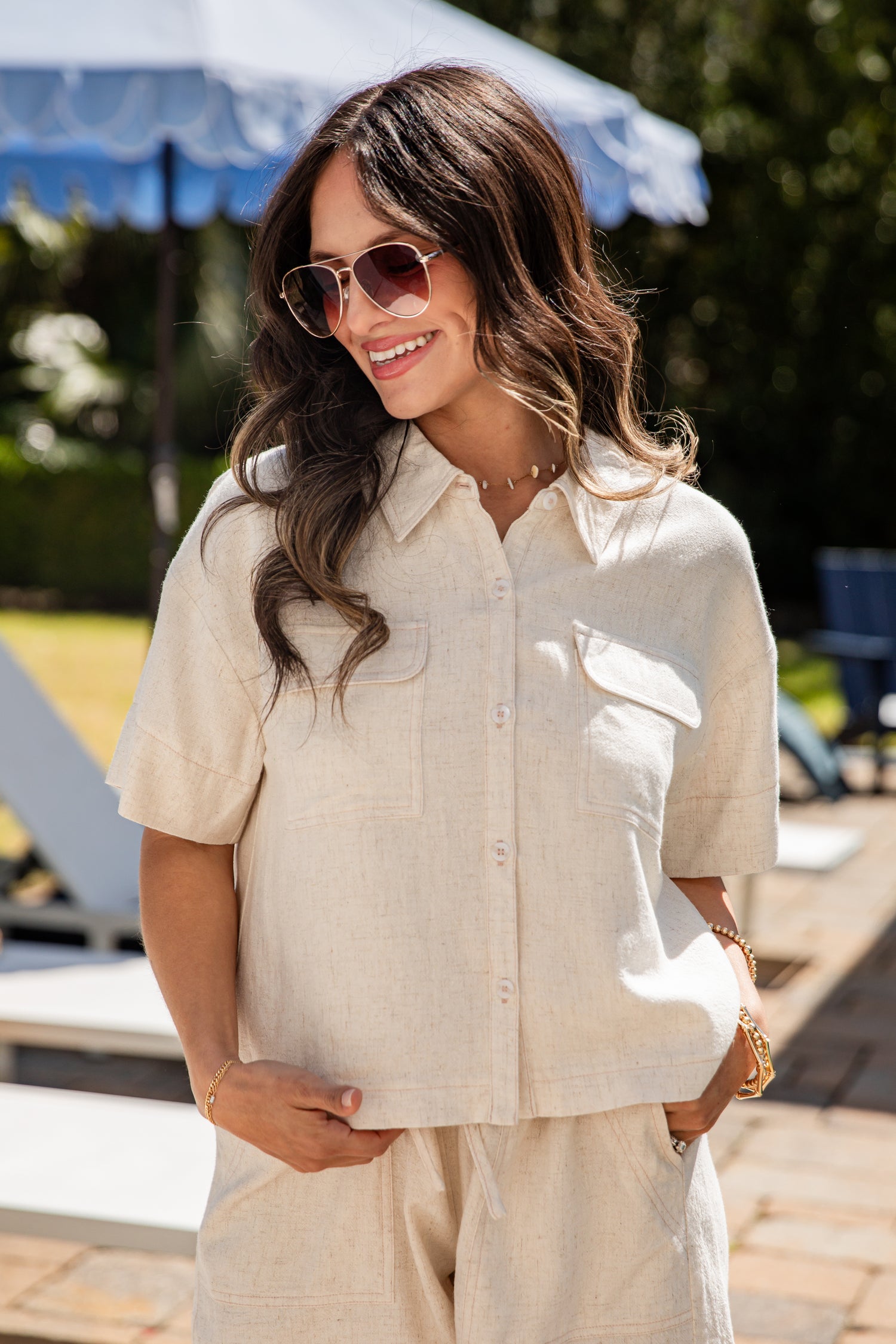 Woman wearing a beige shirt and sunglasses outdoors