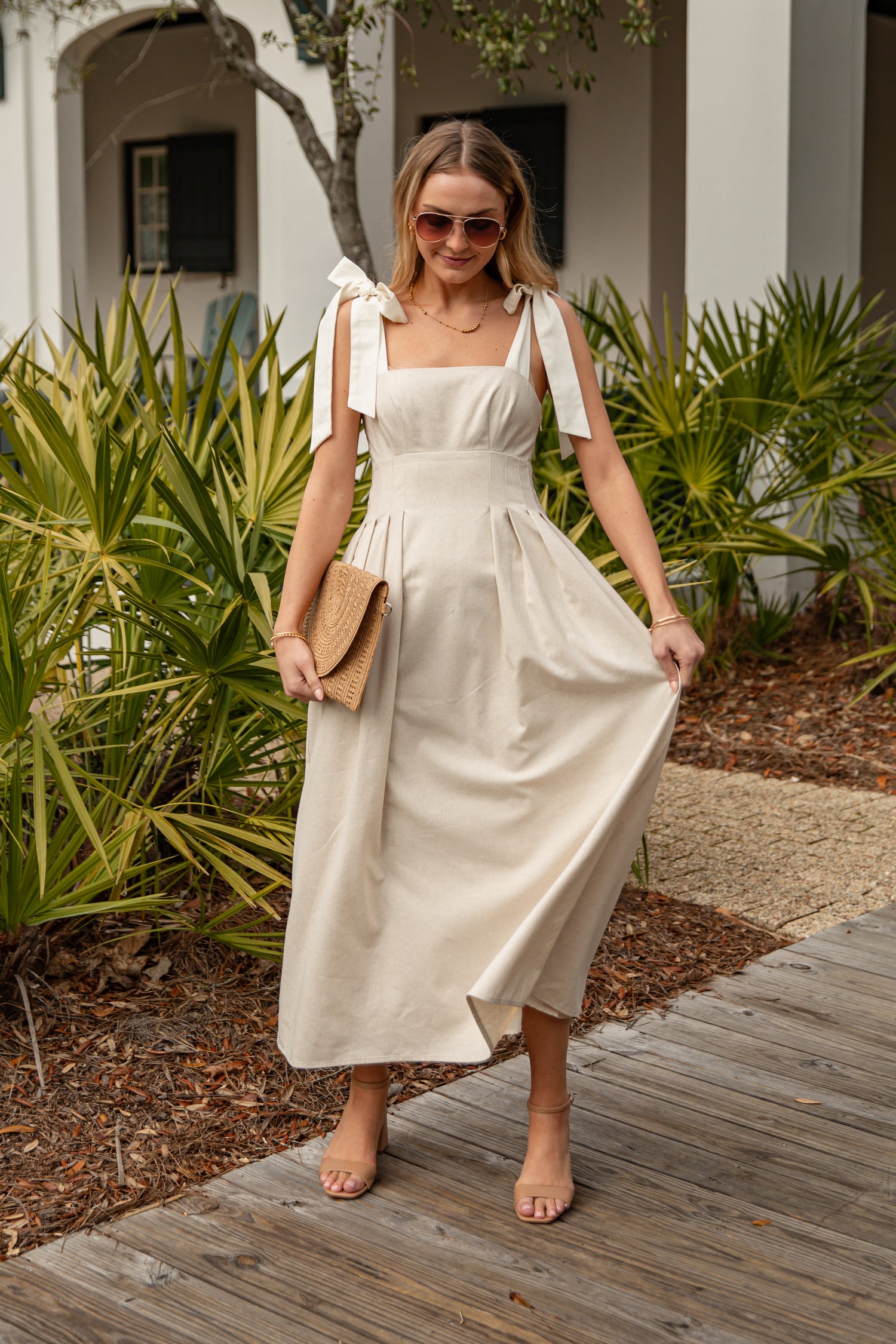 Woman in a white dress standing outdoors with greenery in the background