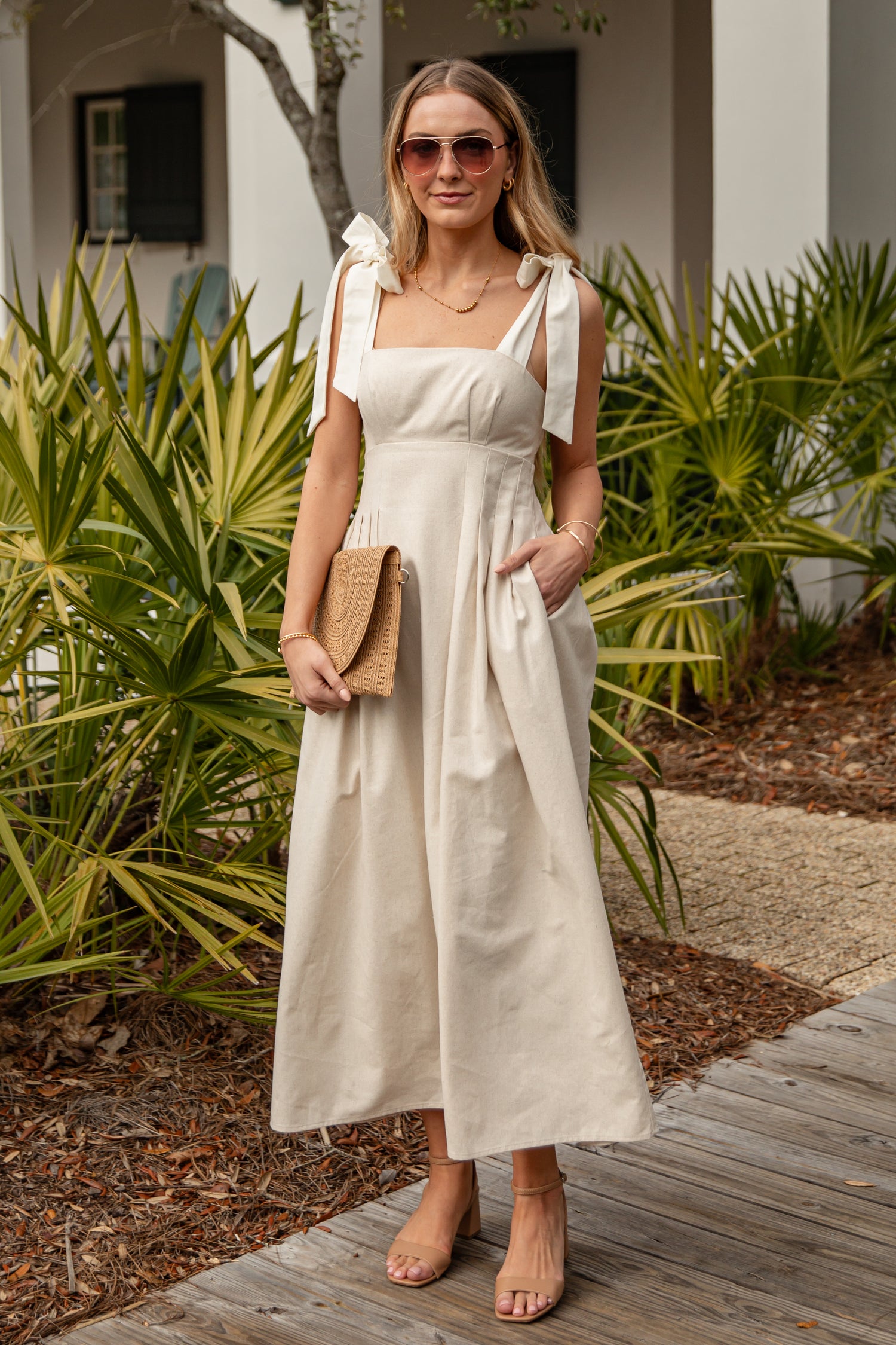 Woman in a white dress standing outdoors with greenery in the background