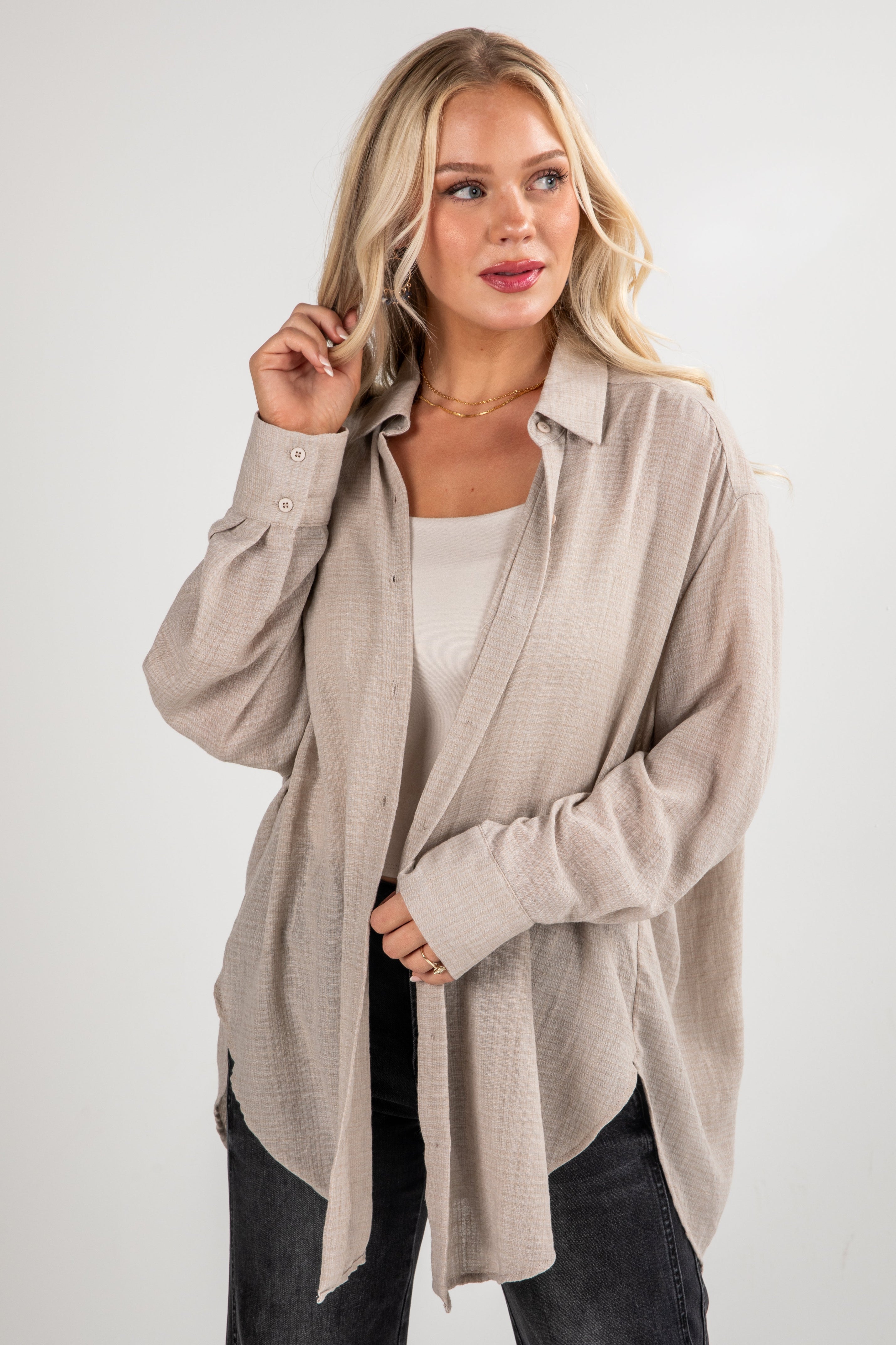 Woman wearing a beige long-sleeve shirt over a white top on a white background