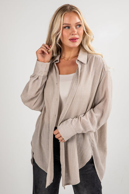 Woman wearing a beige long-sleeve shirt over a white top on a white background