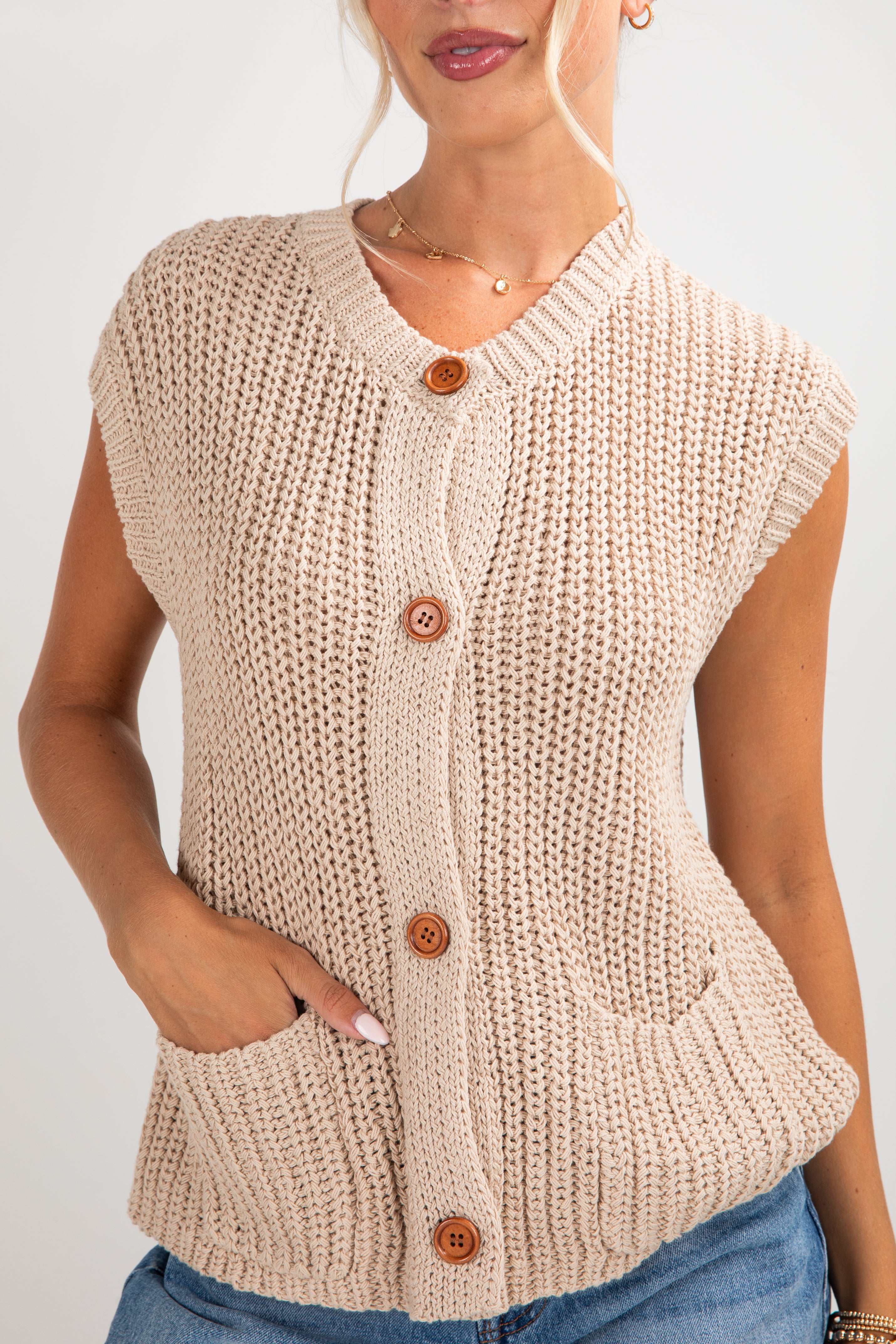 Beige knitted vest with buttons on a plain background