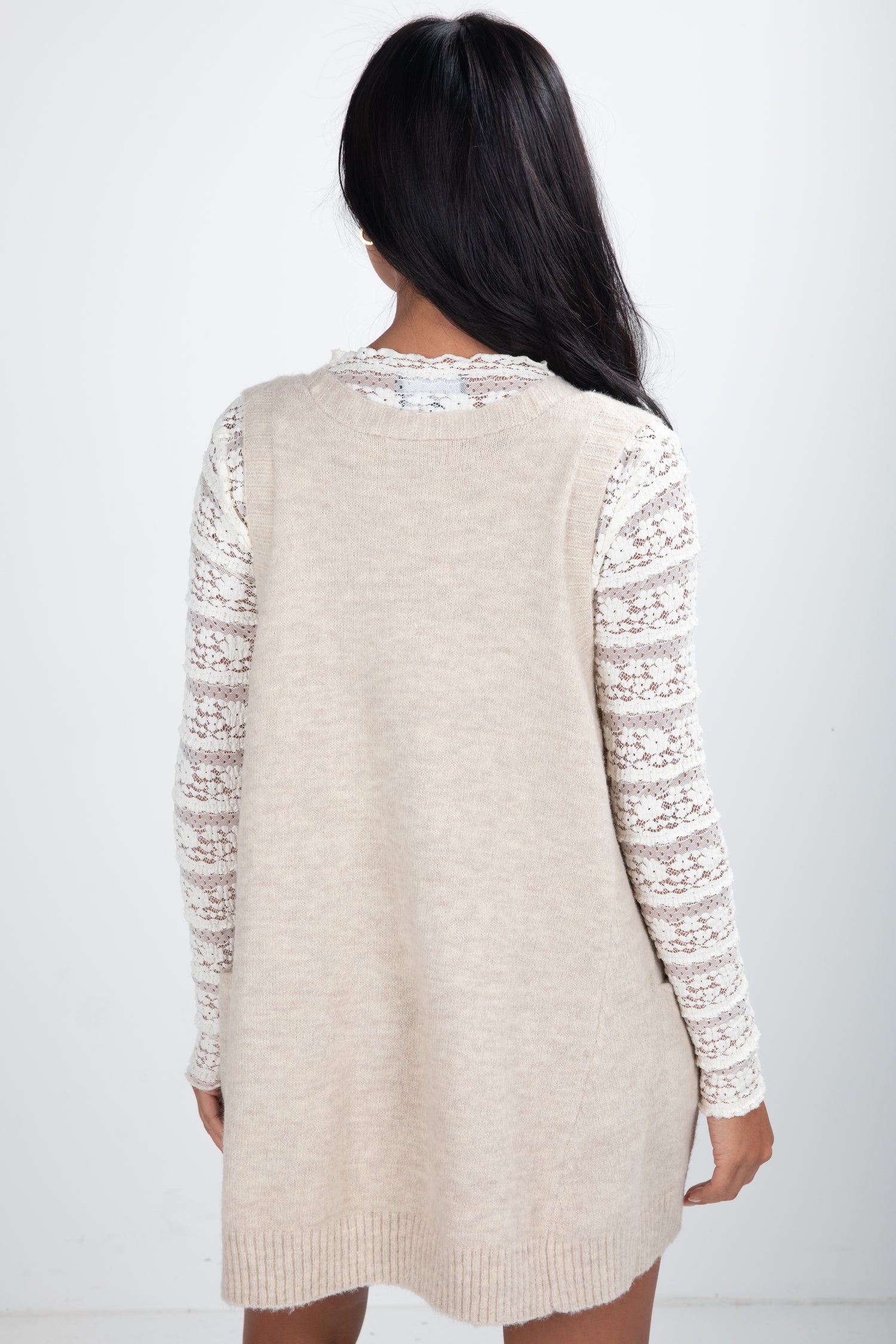 Beige cardigan with lace sleeves worn by a person on a white background