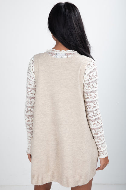 Beige cardigan with lace sleeves worn by a person on a white background