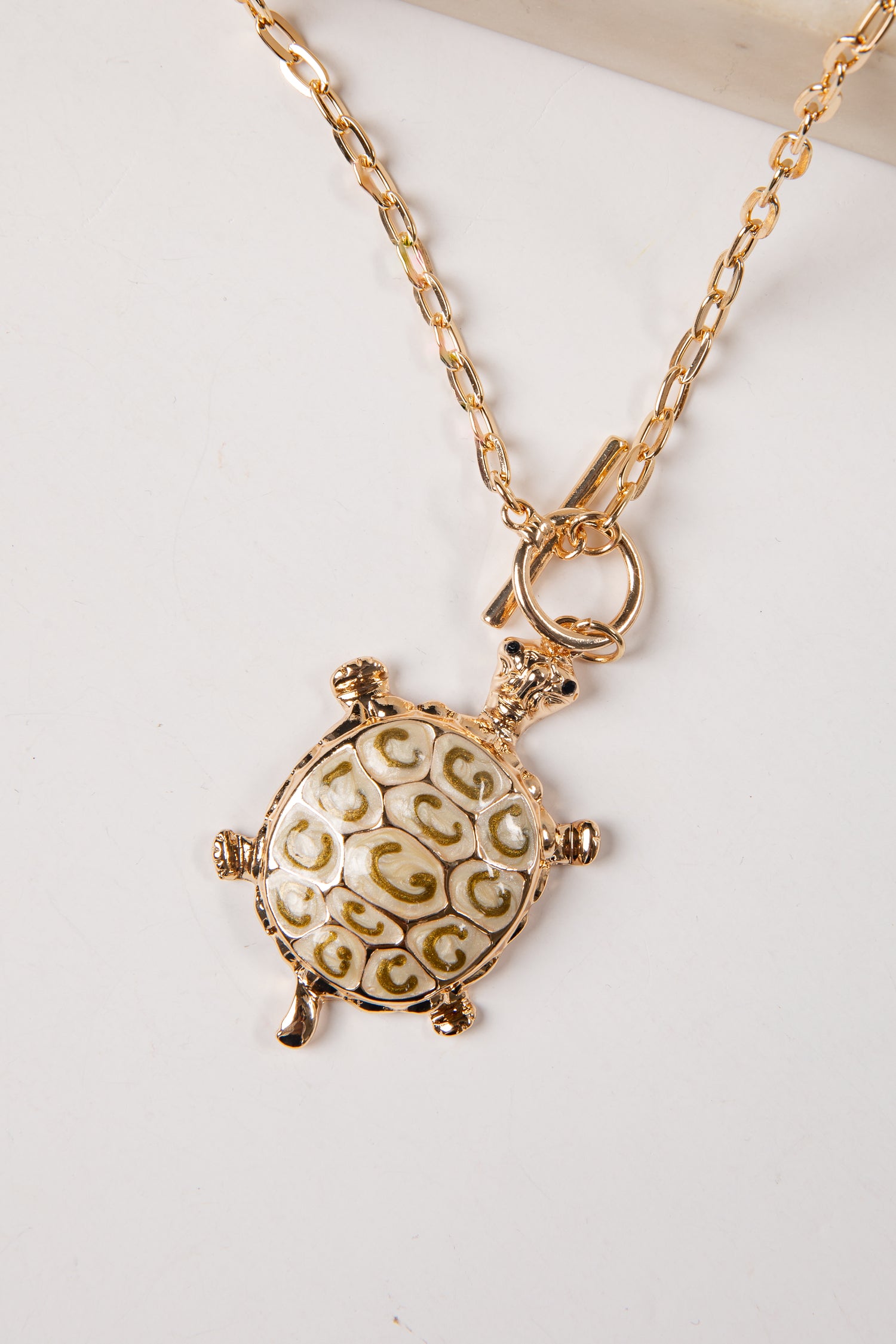 Gold turtle pendant necklace on a white background