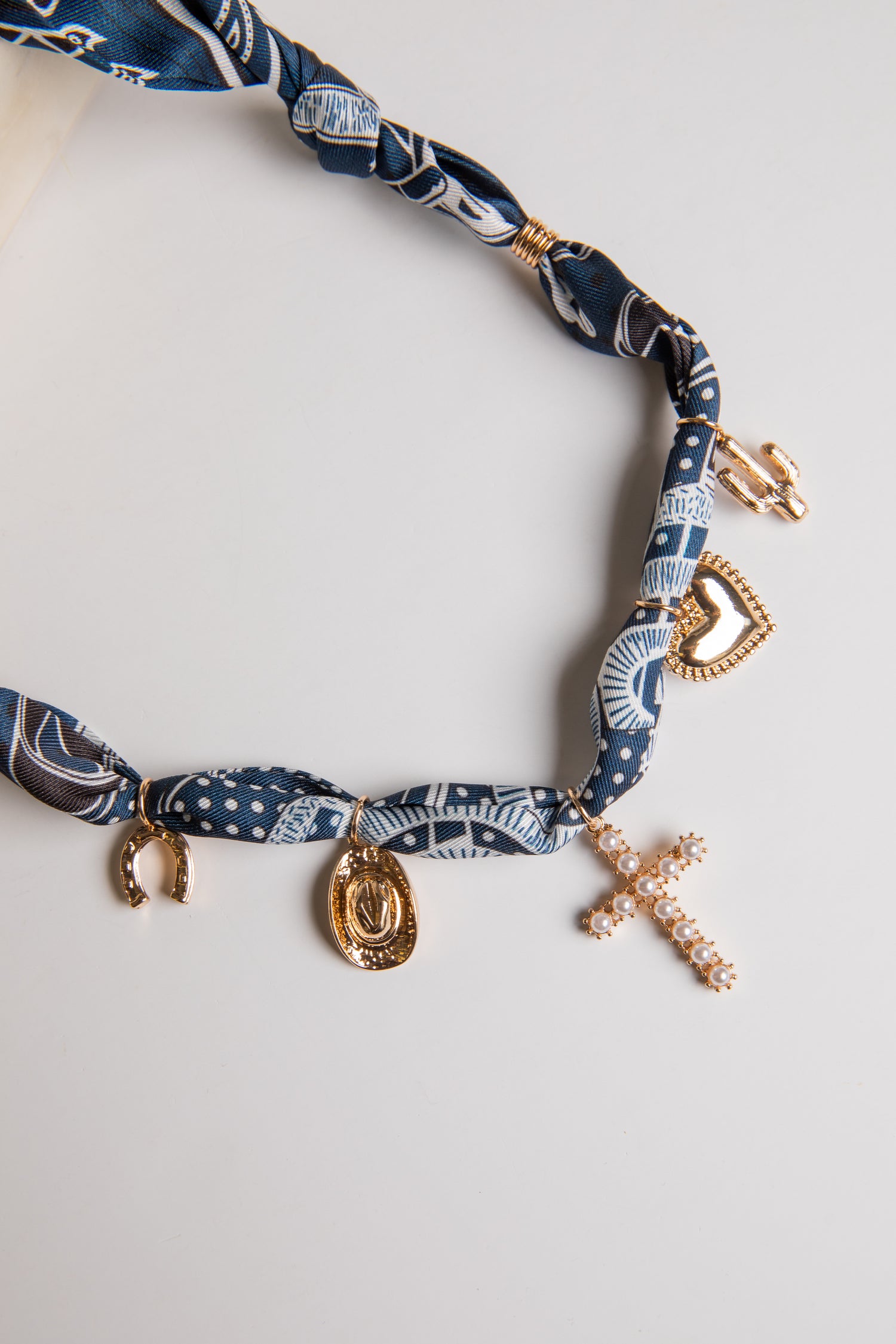 Navy blue patterned headband with gold charms on a light gray background