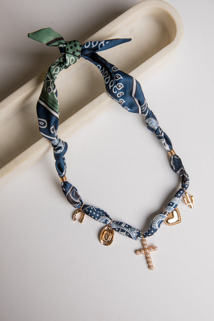 Necklace with blue bandana pattern and gold charms on a white surface