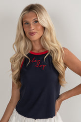 Woman wearing a navy tank top with red text on a plain background